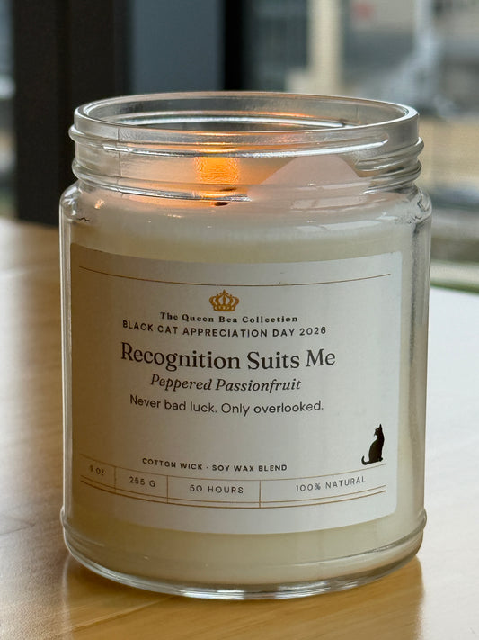 Recognition Suits Me soy candle in Peppered Passionfruit, label facing forward on a plain ground