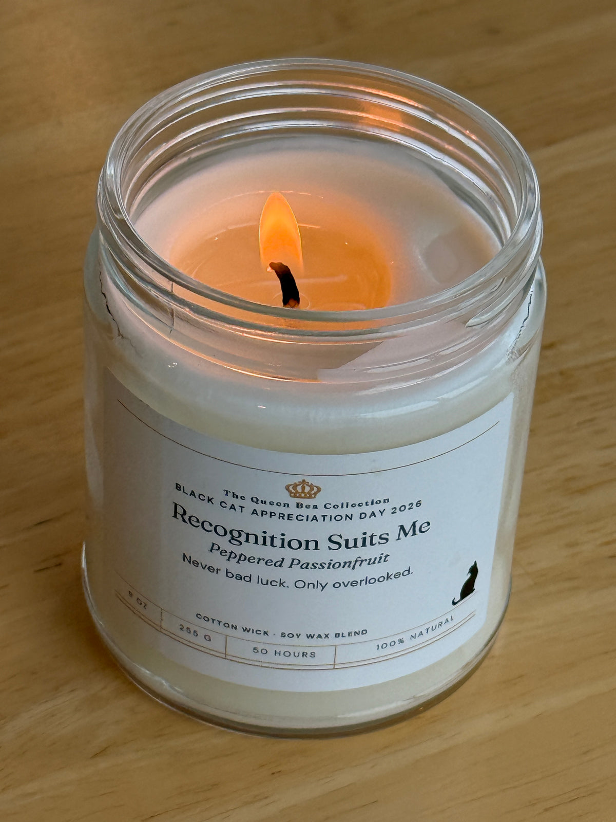 Recognition Suits Me candle lit, showing the melted soy wax and cotton wick