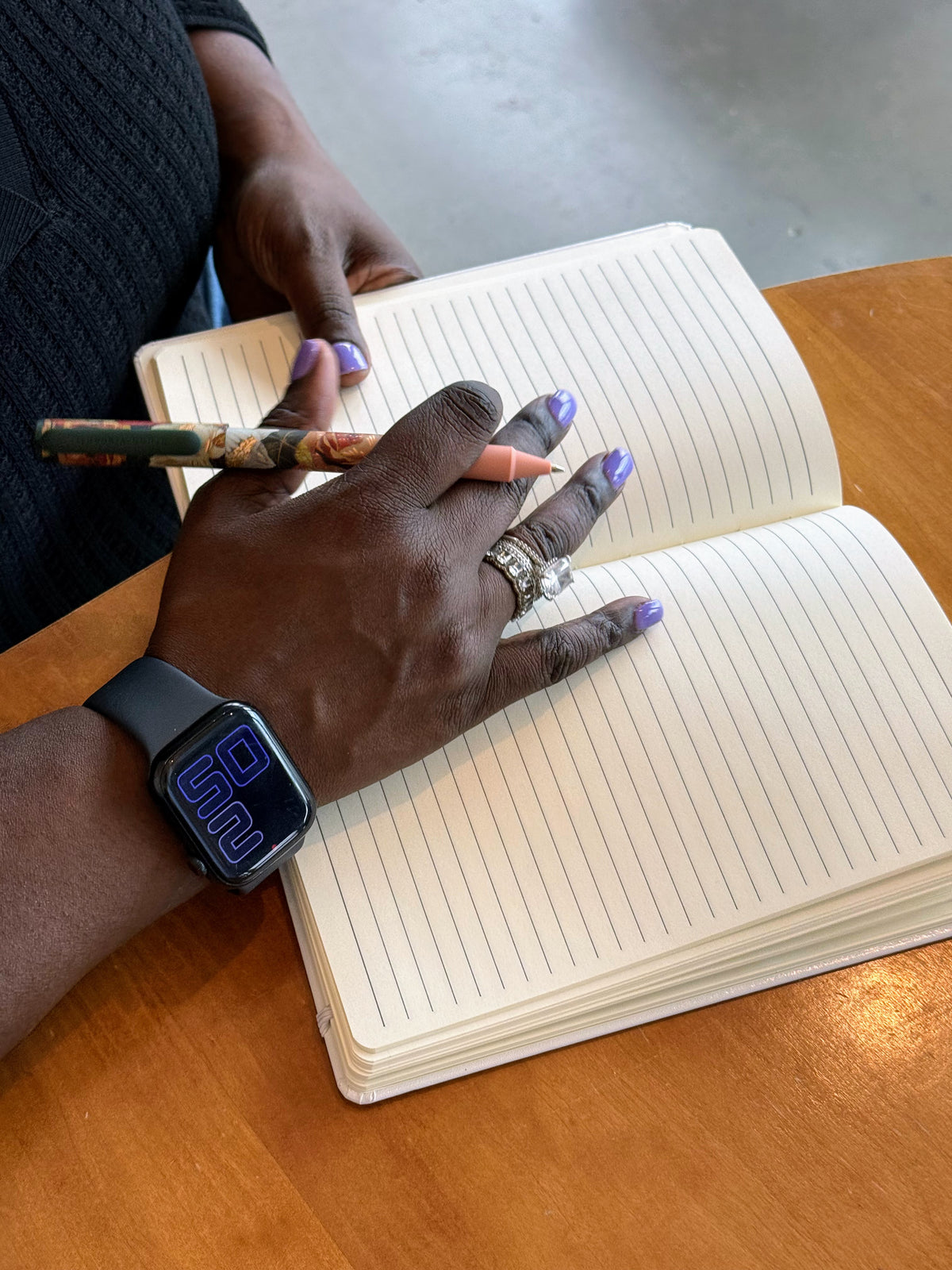 The white Writing Myself a Fan Letter journal open to its ruled pages, a hand holding a pen