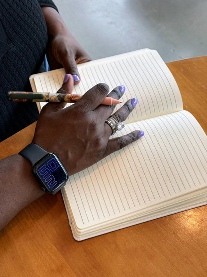 The white Writing Myself a Fan Letter journal open to its ruled pages, a hand holding a pen