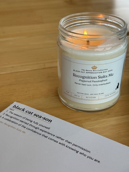 The Black Cat Season notepad with the Recognition Suits Me candle on a clean wood table