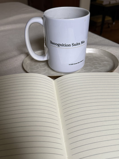 Recognition Suits Me mug beside an open journal with lined pages