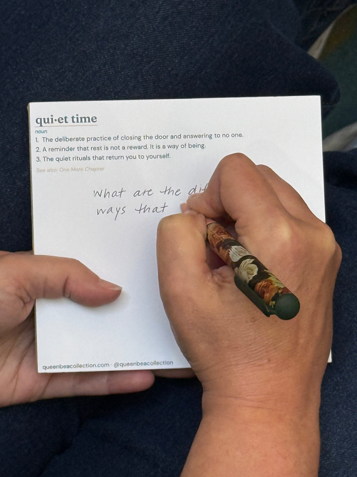 A hand writing on the Quiet Time notepad with a floral pen